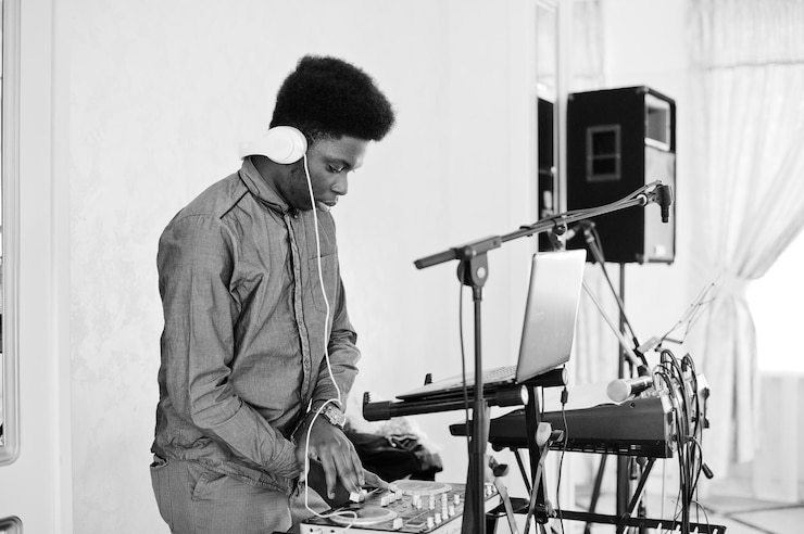 Free Photo african american dj in huge white headphones creating music on mixing panel black and white photo