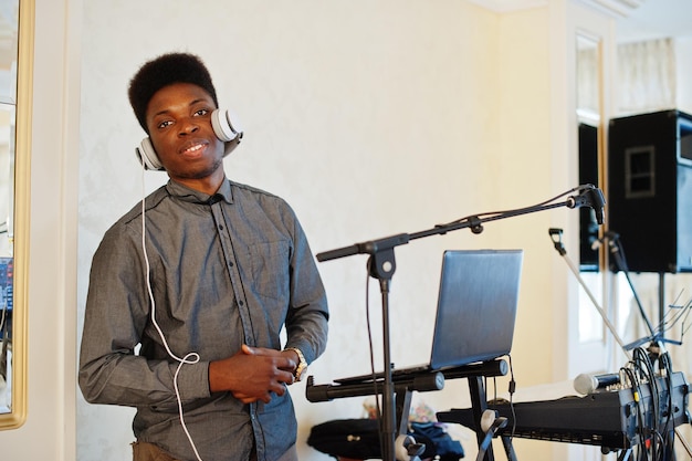 African american dj in huge white headphones creating music on mixing panel