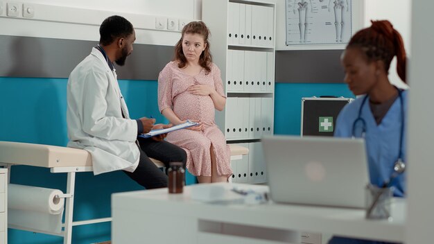 African american doctor consulting pregnant woman on bed