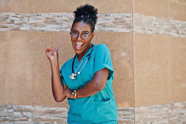 African american doctor female at lab coat with stethoscope posed outdoor against clinic