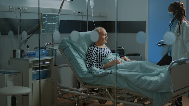 Free photo african american doctor fixing adjustable bed in hospital ward