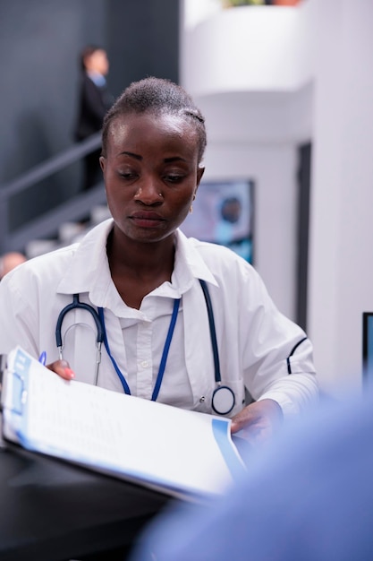 Free photo african american doctor giving medical report to assistant discussing patient symptoms working together at medication treatment in hospital waiting area. medicine service and concept