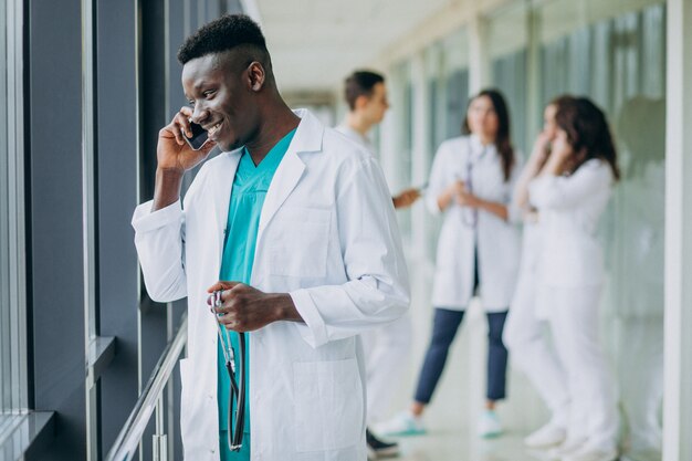 African American doctor man talking by phone, standing in the corridor of the hospital