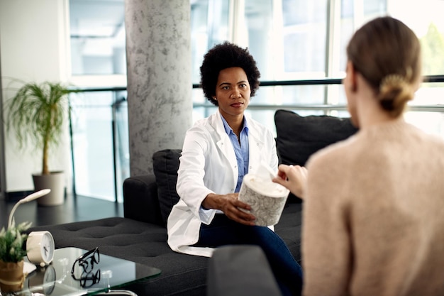 Free photo african american doctor offering tissue to a patient during therapeutic session