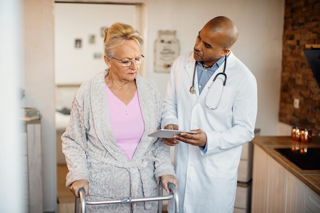 African American doctor and senior woman using digital tablet at nursing home