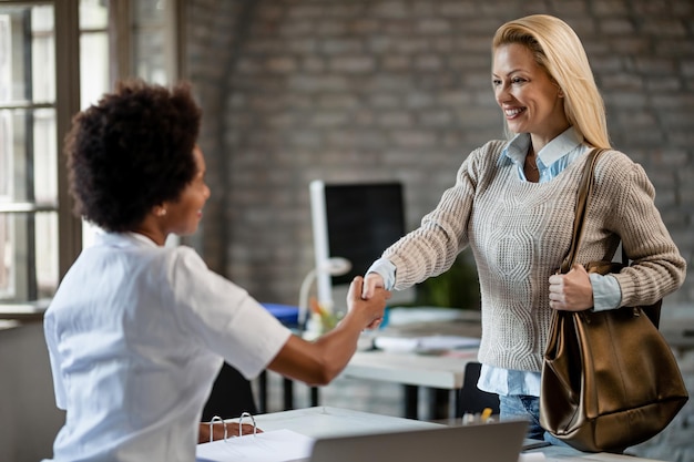 Foto gratuita medico afroamericano che stringe la mano alla sua paziente durante l'incontro presso la clinica il focus è sulla donna felice