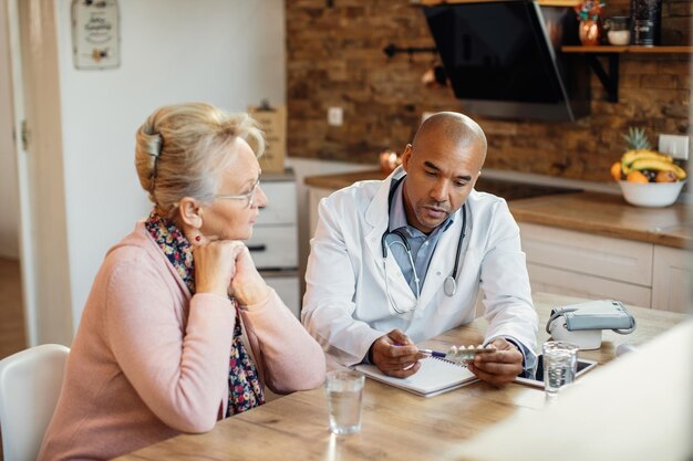 African American doctor talking about medicines with mature woman during home visit