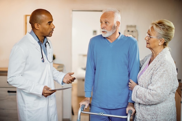 African American doctor talking to elderly couple at nursing home