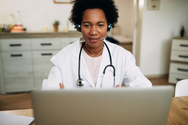 Афроамериканский врач работает на ноутбуке в своем офисе