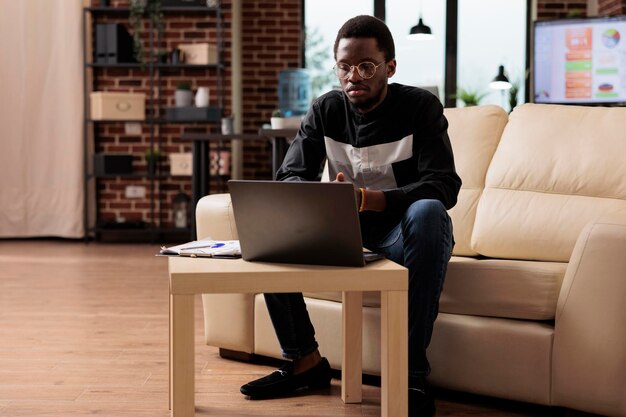 African american employee working on laptop to plan business presentation and new software developing app in cyber security. Office worker using corporate report to send emails