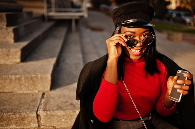 Free photo african american fashion girl in coat and newsboy cap sunglasses posed at street