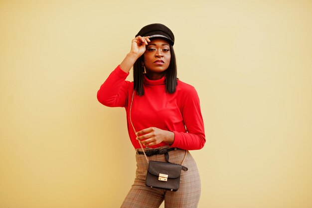 African american fashion girl with newsboy cap posed against yellow background