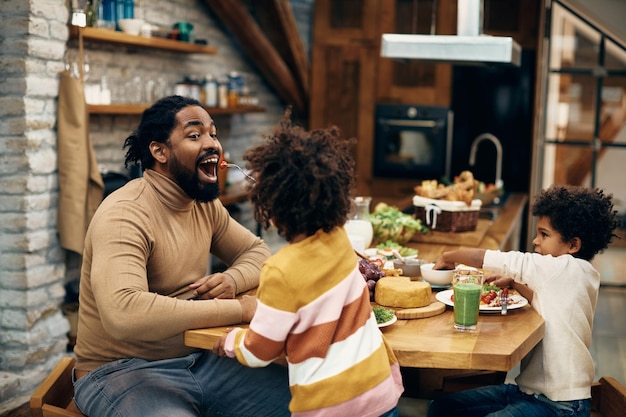 家で食事をしているときに娘に餌を与えられているアフリカ系アメリカ人の父親