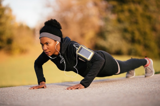 Foto gratuita atleta afroamericana che pratica flessioni nel parco