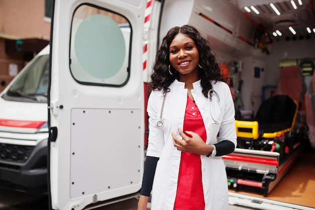 Foto gratuita paramedico femminile afroamericano in piedi davanti all'auto ambulanza