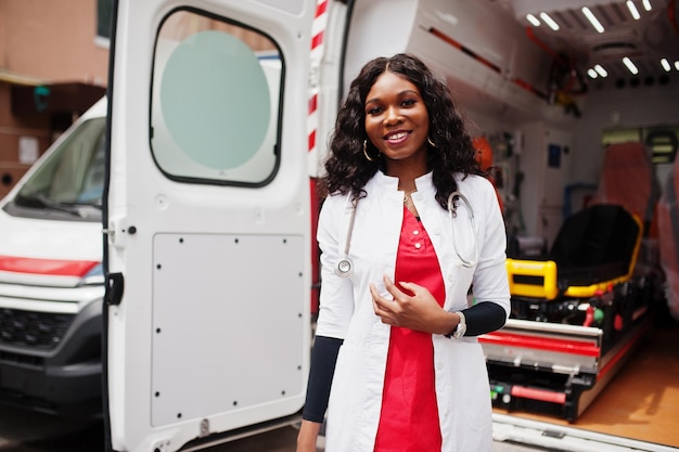 Афро-американский фельдшер, стоящий перед машиной скорой помощи