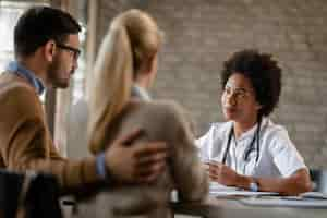 Free photo african american general practitioner having consultations with a couple at medical clinic