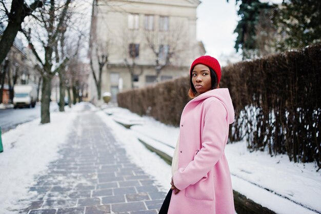 African american girl in red hat and pink coat at street of city on winter day