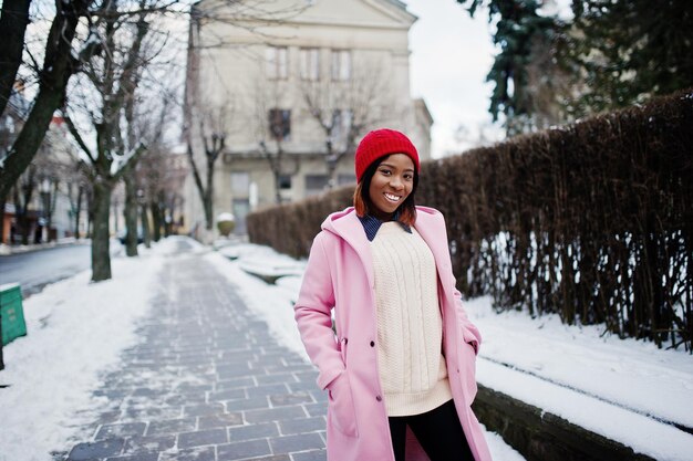 African american girl in red hat and pink coat at street of city on winter day