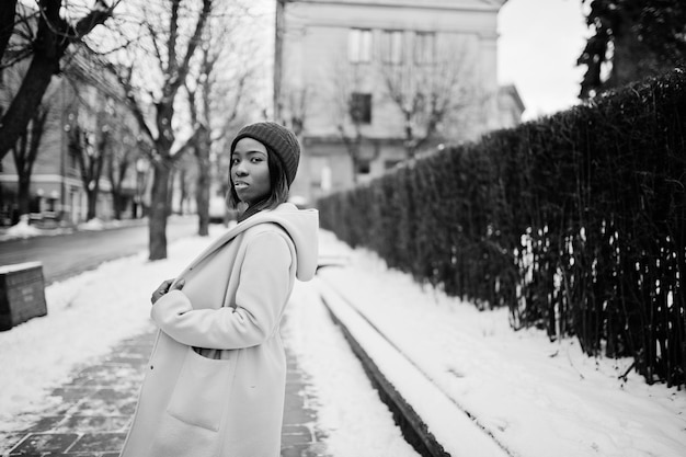 African american girl in red hat and pink coat at street of city on winter day