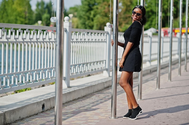 Foto gratuita ragazza afroamericana in occhiali da sole vestiti neri e camicia poste all'aperto donna nera alla moda