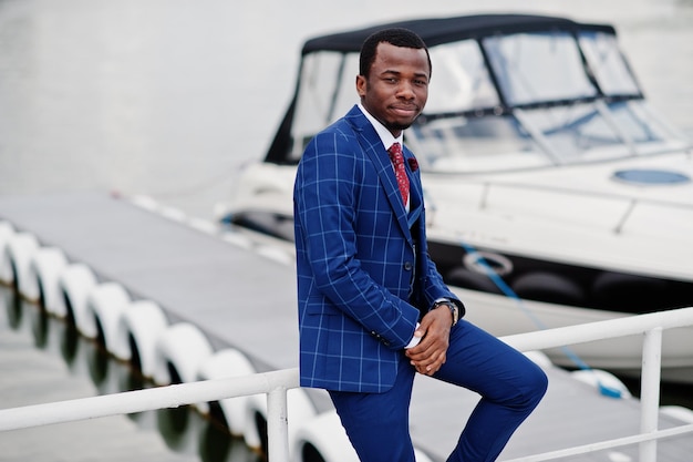 Uomo di successo felice afroamericano a tuta contro yacht uomo d'affari nero ricco