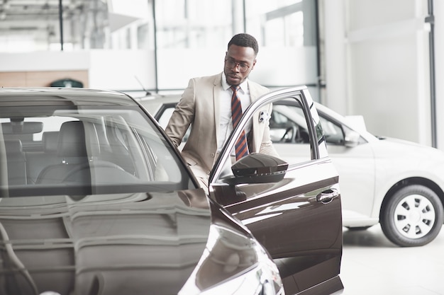Афроамериканец осматривает машину в автосалоне. Хорошая сделка.