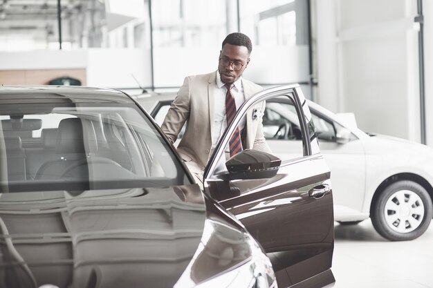 An African American inspects the car at the car dealership. Good bargain.