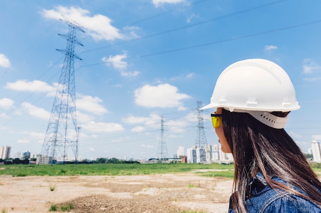 Foto gratuita signora afroamericana in casco di sicurezza vicino alla linea di alta tensione