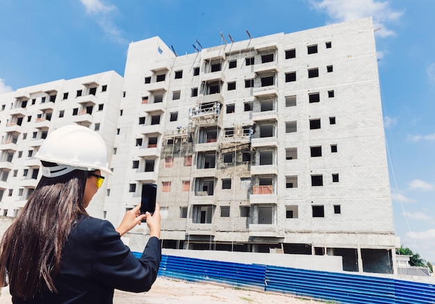 Free photo african american lady in safety helmet taking photo of building under construction