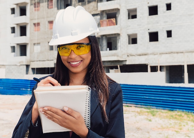 건설중인 건물 근처 노트북에서 안전 헬멧 쓰기에 아프리카 계 미국인 여자