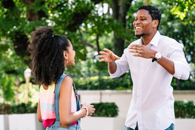 African american little girl with her father having good time together outdoors on the street.