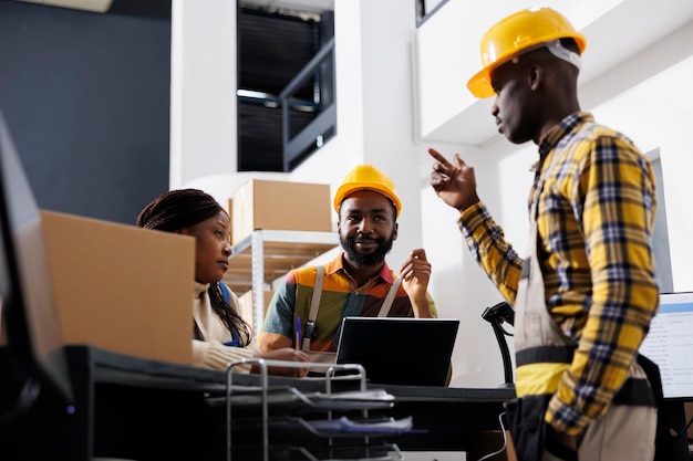 African american logistics managers team dicussing goods distribution at warehouse reception. Post office men and woman workers planning stock supply while chatting at counter desk