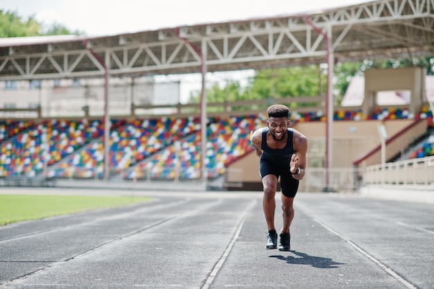 スタジアムでランニングトラックを一人でレースするスポーツウェアのアフリカ系アメリカ人男性アスリート