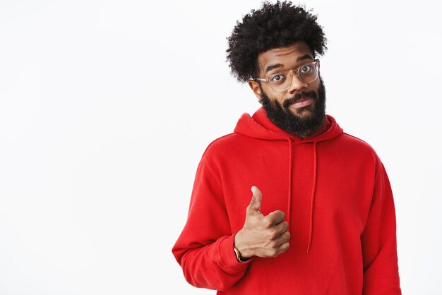 african american male project manager in glasses with beard smiling in approval showing thumbs up gesture, liking good artwork on gray wall.