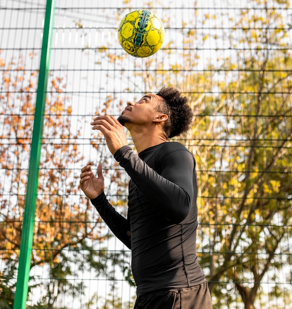 Uomo afroamericano che fa i trucchi con un pallone da calcio