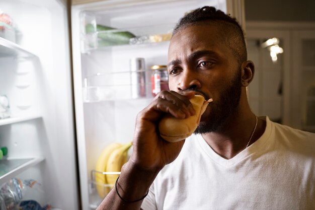 african american man eating from the fridge at night