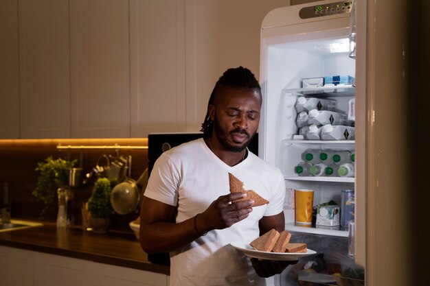 밤에 냉장고에서 먹는 아프리카계 미국인 남자