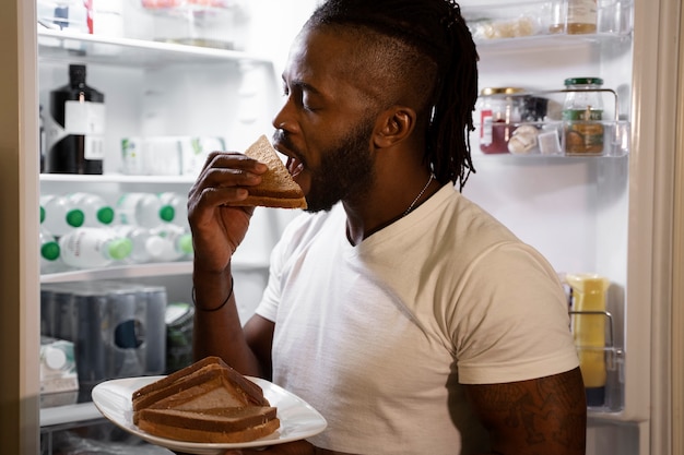 無料写真 夜に冷蔵庫から食べるアフリカ系アメリカ人の男