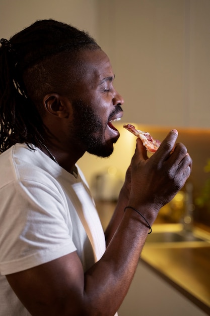 African american man eating pizza late at night