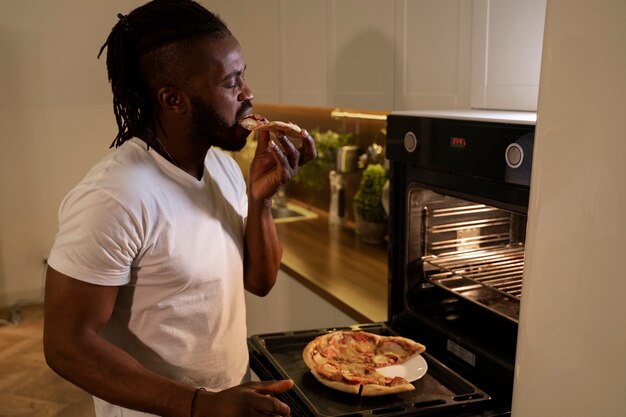 African american man eating pizza late at night