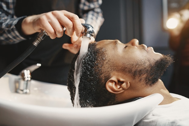 African American man. Guy sitting on a chair. Wash hair.