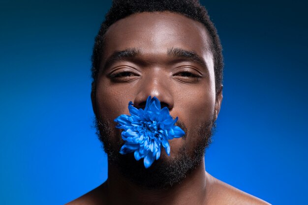 African american man holding a blue flower