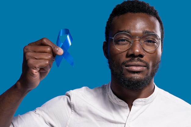 Free photo african american man holding a blue ribbon