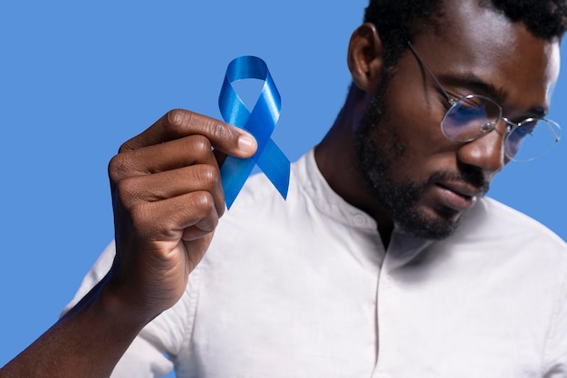 African american man holding a blue ribbon