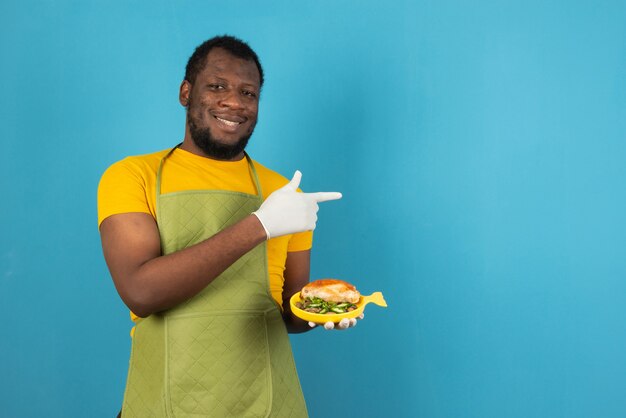 手と指で幸せな水色の壁の上に食事を持って保持しているアフリカ系アメリカ人の男性。