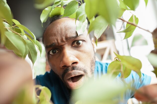 Афро-американский мужчина ищет что-то в необычных местах у себя дома