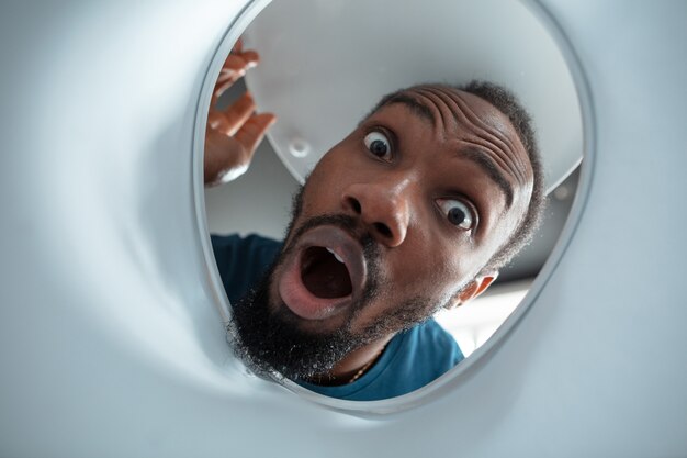 African-american man looking for something in unusual places at his home