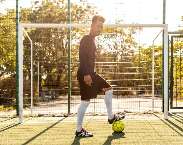 Foto gratuita uomo afroamericano che gioca con un pallone da calcio all'esterno