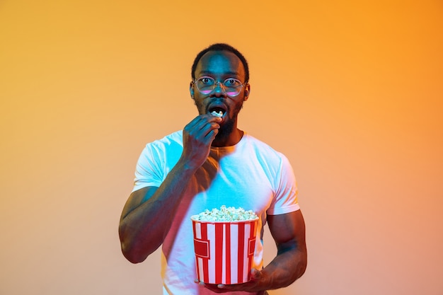 African american man portrait isolated on gradient orange in neon light